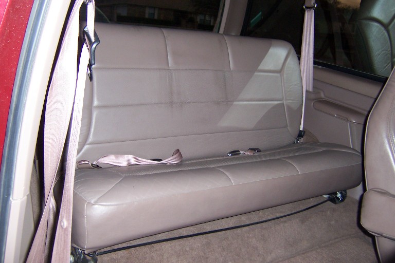 Tan leather rear bench seat inside an SUV, viewed through the open door