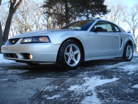 1998 Ford Taurus - A silver Ford Mustang is parked on a road with snow and ice on the ground.