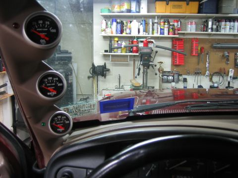 1996 Ford Bronco - A-pillar gauges for oil, water, and transmission temperature are visible inside a vehicle, with a workshop in the background.