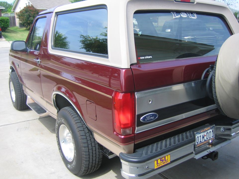 Maroon and tan Ford Bronco with a spare tire on the back
