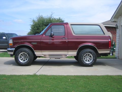 1996 Ford Bronco - Side profile of a maroon 1996 Ford Bronco, a two-tone paint scheme with a tan removable top.