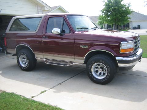 1996 Ford Bronco - This Ford Bronco is parked in a driveway with a house and trees in the background.