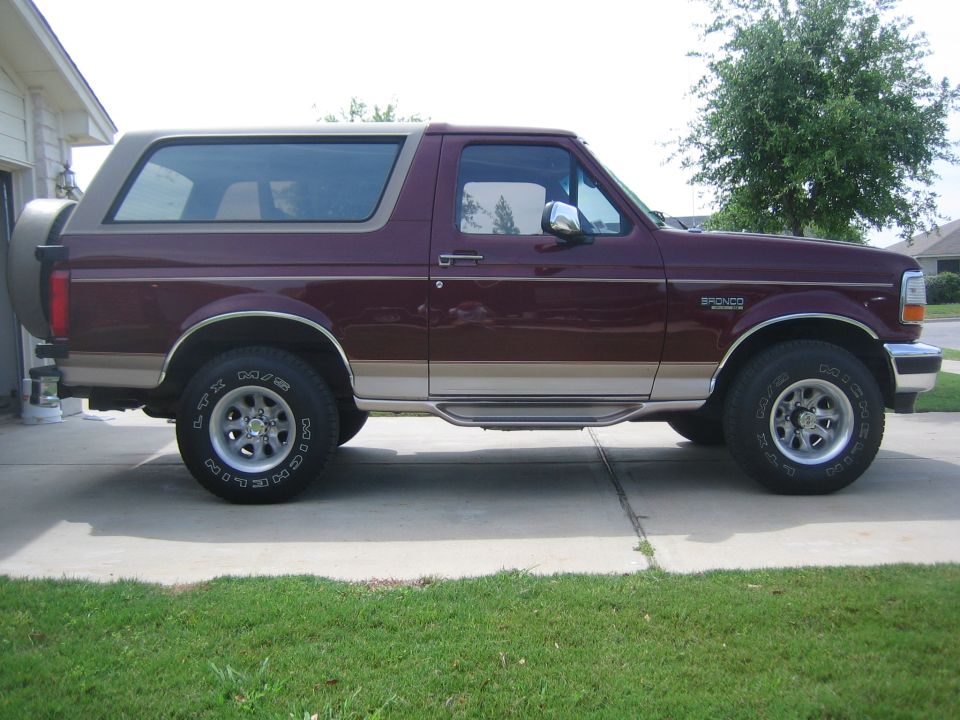 Maroon and tan 1996 Ford Bronco SUV parked on a driveway, side view