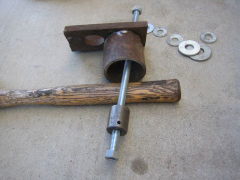 1996 Ford Bronco - A collection of metal parts and a hammer are assembled into a makeshift tool on a concrete surface.