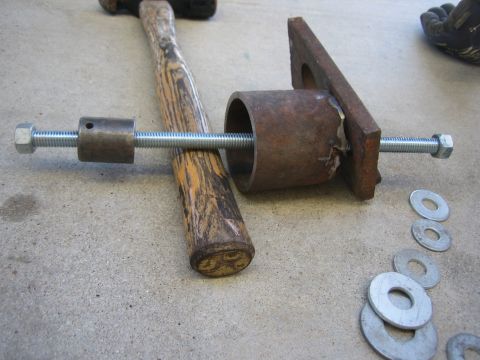 1996 Ford Bronco - A homemade tool, likely for automotive work, is laid out on a concrete surface with a hammer and washers.