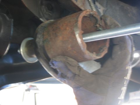 1996 Ford Bronco - Close-up of a gloved hand manipulating a rusted metal pipe with a threaded rod inserted, likely during a repair or modification.