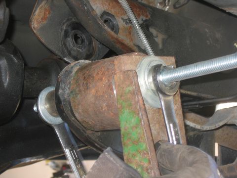 1996 Ford Bronco - Close-up of a wrench being used to install a suspension component on a vehicle.