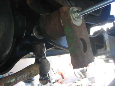 1996 Ford Bronco - Mechanic uses a hammer on a rusty suspension component during a lift installation.