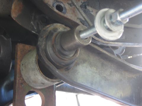 1996 Ford Bronco - A close-up view of a vehicle's suspension system, showing a bolt being installed into a rusty component.