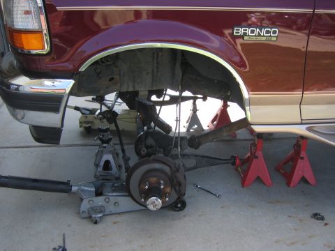 1996 Ford Bronco - The front suspension of a 1996 Ford Bronco is disassembled and supported by various jacks and stands.