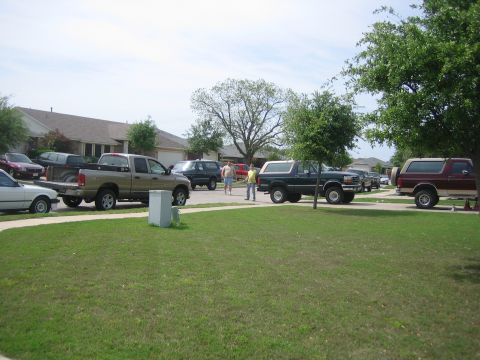 1996 Ford Bronco - A dark green 1996 Ford Bronco is parked on a suburban street alongside other vehicles.