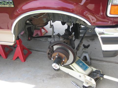 1996 Ford Bronco - The front wheel assembly of a 1996 Ford Bronco is elevated on jack stands for maintenance.