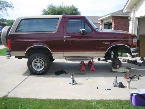 1996 Ford Bronco - Side view of a 1996 Ford Bronco undergoing maintenance, lifted on jack stands.