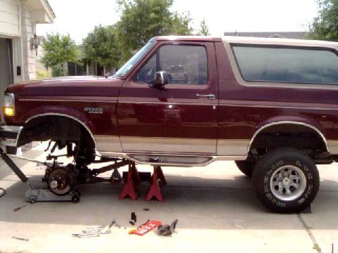 1996 Ford Bronco - The front suspension of a 1996 Ford Bronco is being worked on, with the vehicle elevated on jack stands.