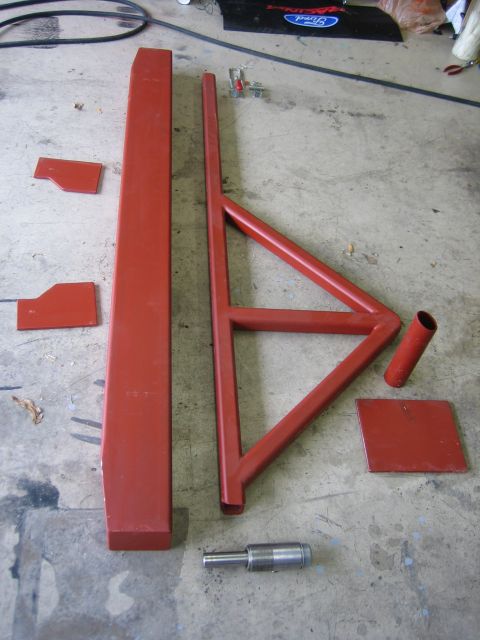 1996 Ford Bronco - Various red-painted metal components are arranged on a workshop floor, possibly for assembly or repair.