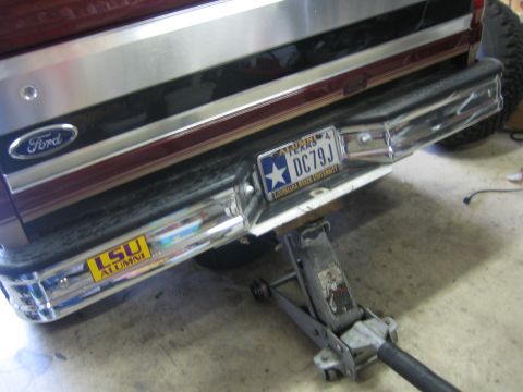 1996 Ford Bronco - The rear bumper of a vehicle, a Ford logo and a Texas license plate, is supported by a jack.