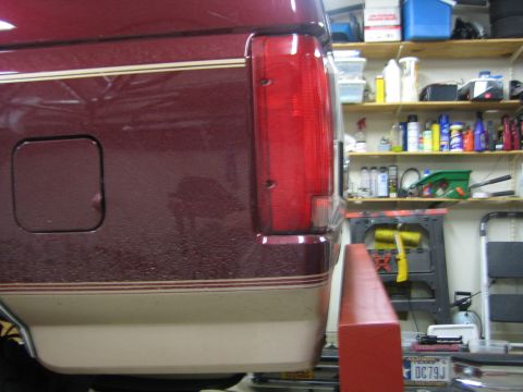 1996 Ford Bronco - The rear quarter panel and taillight of a maroon 1996 Ford Bronco are visible, showing its distinctive dual-tone paint scheme.