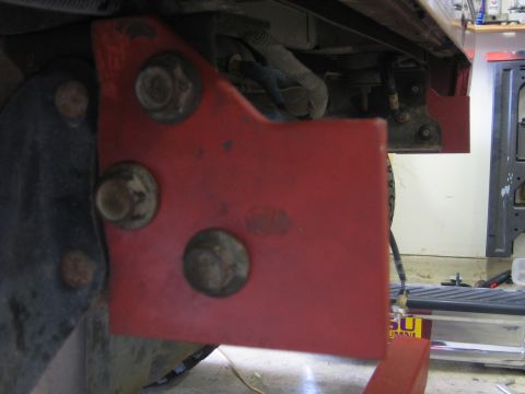 1996 Ford Bronco - Close-up of a red metal bracket with visible bolts, likely a vehicle part.