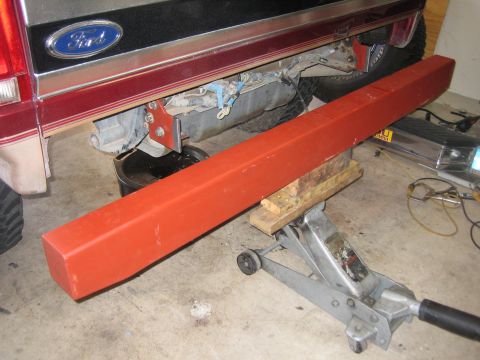 1996 Ford Bronco - A red bumper is supported by a jack beneath a 1996 Ford Bronco.