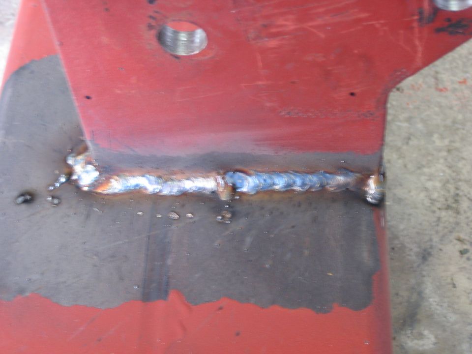 Red metal bracket with a visible weld seam and a threaded hole