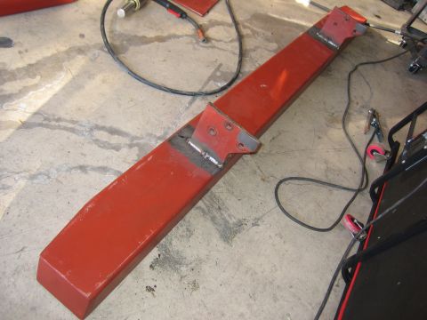 1996 Ford Bronco - A red metal bumper part, likely for a vehicle, is shown on a concrete floor with welding equipment nearby.
