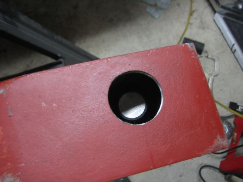 1996 Ford Bronco - A red metal component with a hole drilled through it, likely part of a larger assembly or modification.