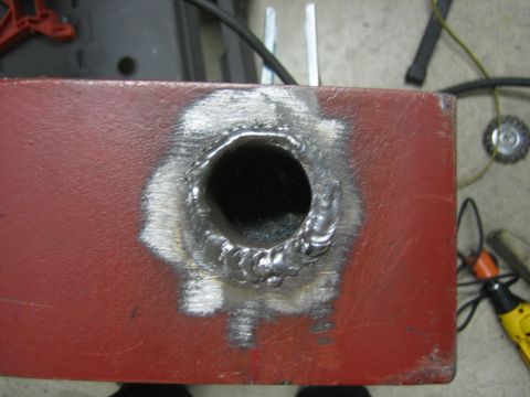 1996 Ford Bronco - A close-up view shows a freshly welded hole on a red metal component, with tools visible in the background.