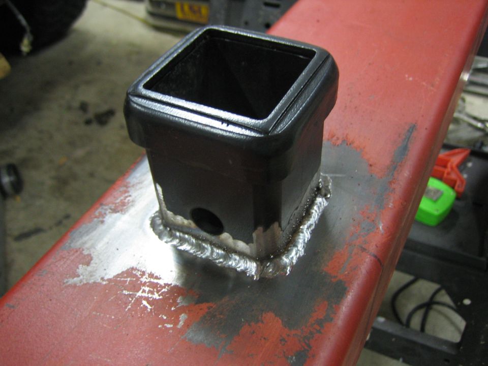 Trailer hitch receiver welded to a red metal beam