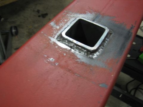 1996 Ford Bronco - Close-up of a square steel tube welded into a red metal beam, likely part of a custom build.