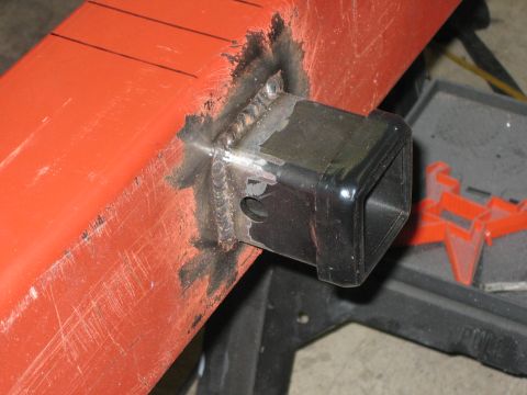 1996 Ford Bronco - A close-up view of a newly welded trailer hitch receiver attached to an orange metal bar.