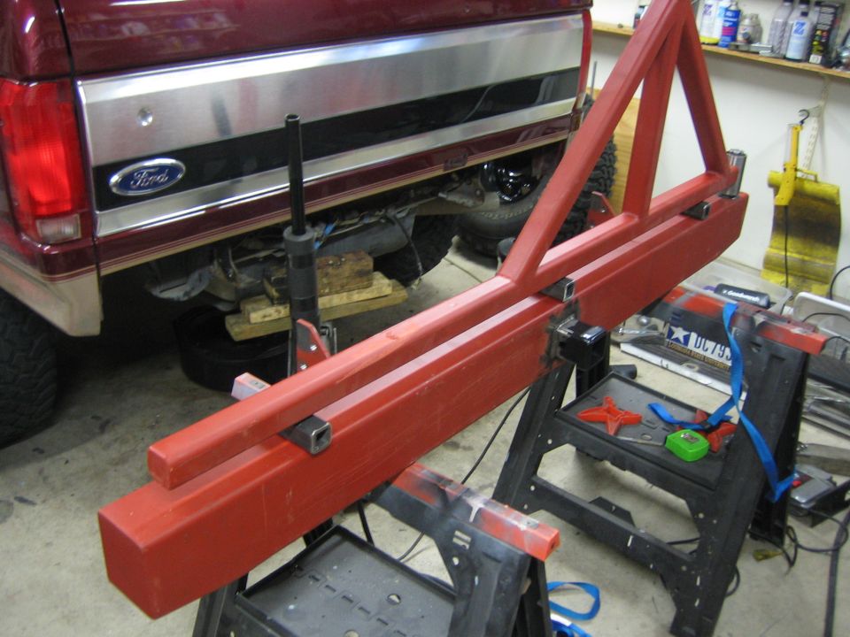 Red metal fabrication project on sawhorses next to the rear of a Ford truck