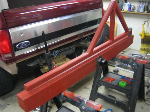 1996 Ford Bronco - A red custom-built rear bumper assembly is shown in front of a Ford truck's tailgate.