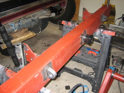 1996 Ford Bronco - Red metal frame with welded brackets and a black cube attached, resting on sawhorses.