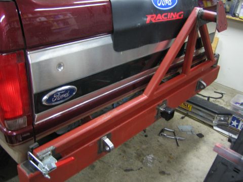 1996 Ford Bronco - Custom red tire carrier attached to the rear of a maroon Ford Bronco, showing a Ford badge and racing sticker.