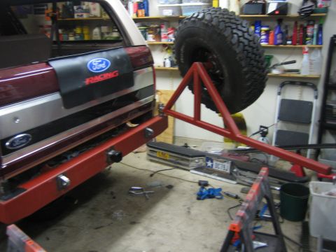 1996 Ford Bronco - The rear of a Ford Bronco is shown with a custom-mounted spare tire carrier and a Ford Racing mud flap.