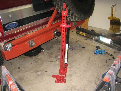 1996 Ford Bronco - A red aftermarket bumper is attached to a vehicle with a hi-lift jack and spare tire. The Ford emblem is visible on the tailgate.