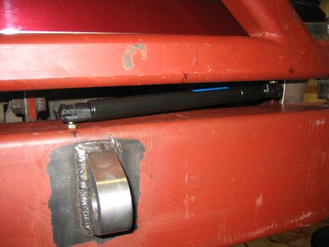 1996 Ford Bronco - Close-up of a red rear bumper assembly a black gas strut and a welded mounting bracket.