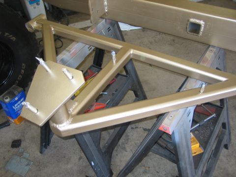 1996 Ford Bronco - Custom rear bumper swing-away tire carrier frame, gold painted, on sawhorses. Tire and lacquer thinner can visible.