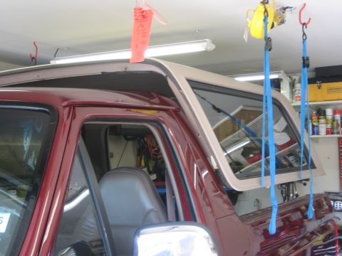 1996 Ford Bronco - The removable top of a Ford Bronco is being lifted by straps in a garage setting.