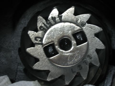 1996 Ford Bronco - A close-up of a metal gear with visible stamped markings, likely a component from a vehicle's drivetrain.