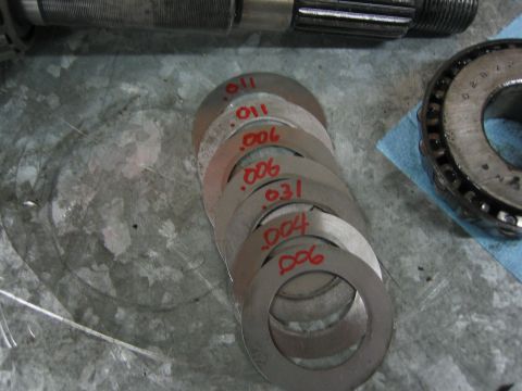 1996 Ford Bronco - A collection of shims, some marked with their thickness in inches, are laid out next to a roller bearing.