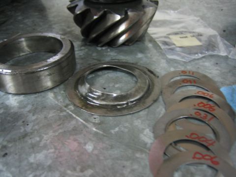 1996 Ford Bronco - Differential ring gear, pinion gear, bearing, and shims with thickness markings are laid out on a workbench.