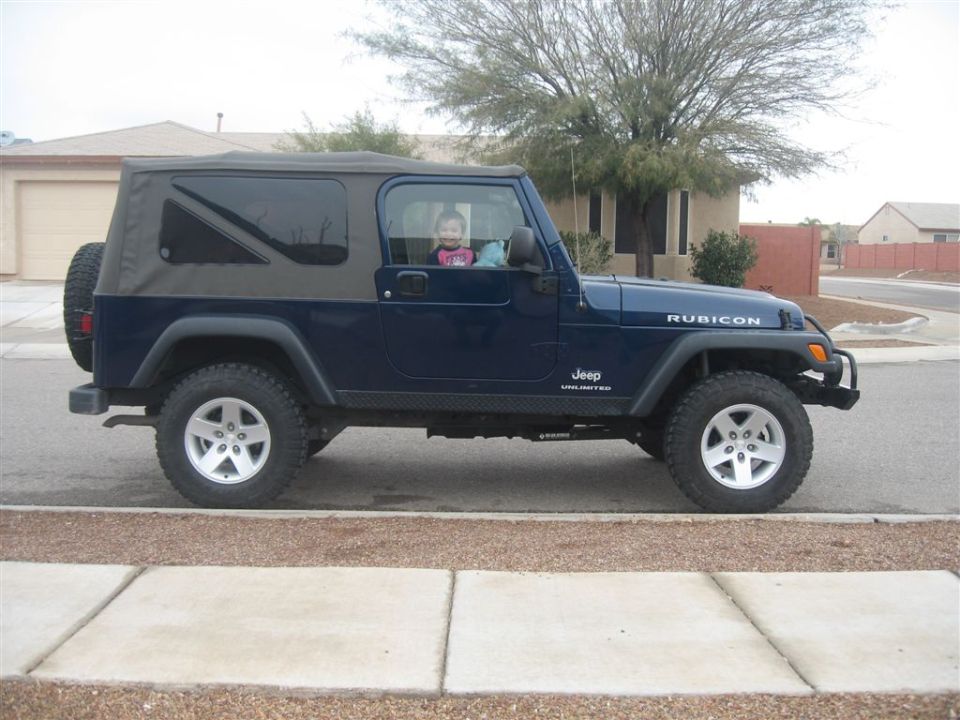 Dark blue Jeep Wrangler Unlimited Rubicon, side view, at a suburban curb