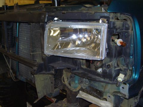 1996 Ford Bronco - The front of a vehicle is shown with the headlight assembly removed, exposing the radiator and wiring.