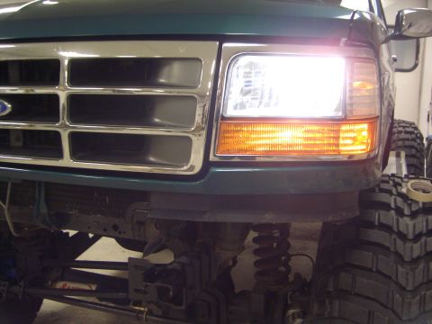 1996 Ford Bronco - Front view of a green Ford F-150 showing its chrome grille and headlight assembly.