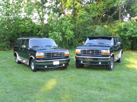 1995 Ford C-350 (Centurion Conversions) - Two dark green Ford C-350 Centurion Conversions SUVs are parked on a grassy lawn with trees in the background.