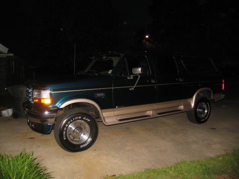 1995 Ford C-350 (Centurion Conversions) - A dark green Ford Bronco with tan lower trim is parked on a driveway at night.