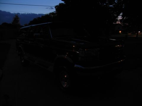 1995 Ford C-350 (Centurion Conversions) - A dark Ford F-Series truck is parked outside at dusk, showing its front grille and chrome details.