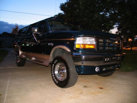 1995 Ford C-350 (Centurion Conversions) - Dark green 1995 Ford C-350 (Centurion Conversions) truck parked outside at twilight.