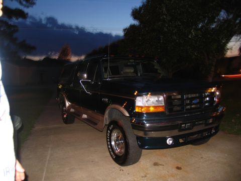 1995 Ford C-350 (Centurion Conversions) - A dark green Ford Bronco is parked on a concrete driveway as dusk settles.